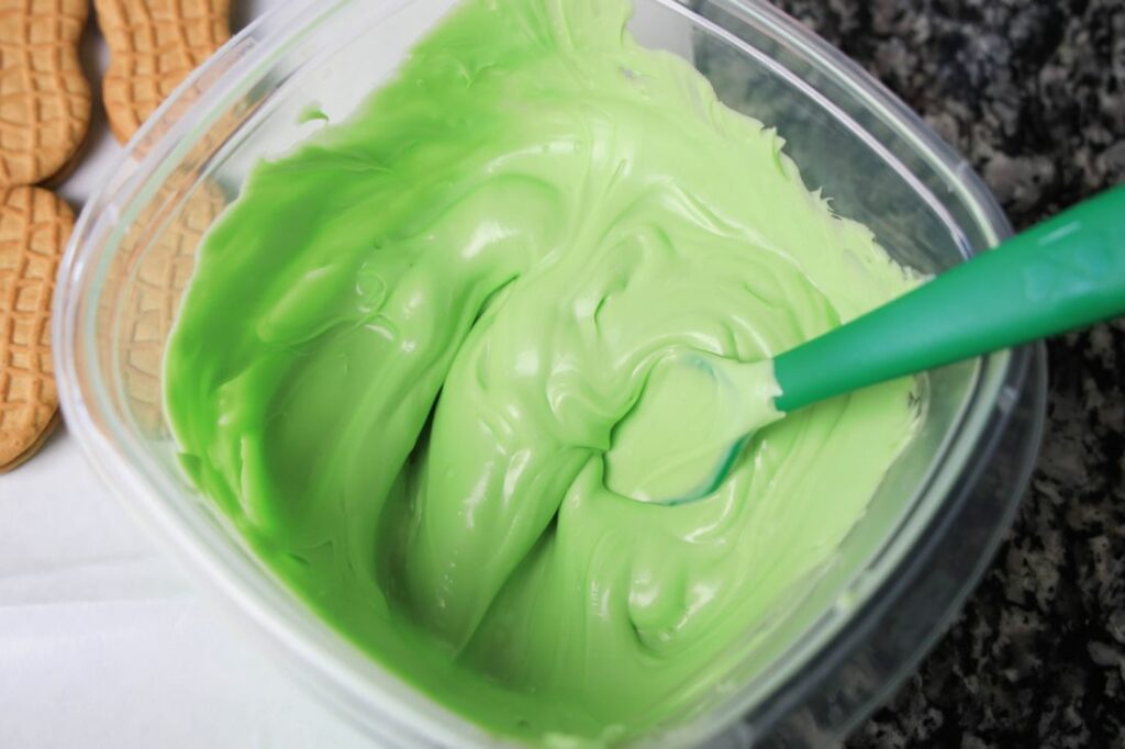 Melted light green candy melts in a plastic bowl.