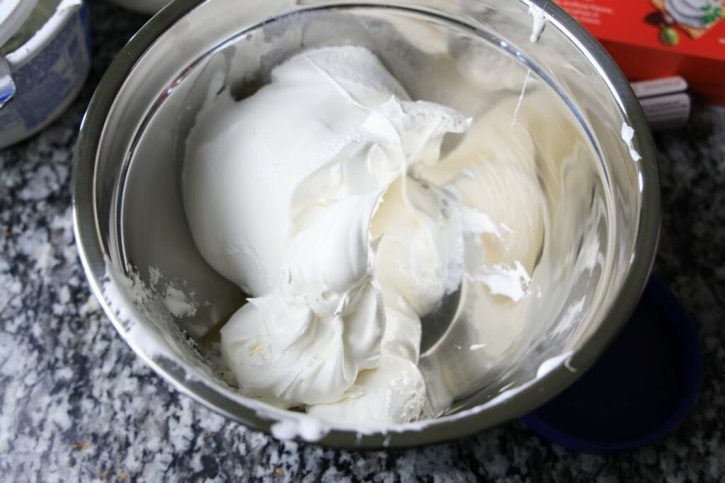 Cool whip and marshmallow fluff in a metal bowl.