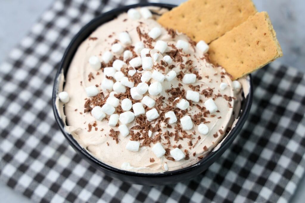Hot Chocolate dip made with whipped topping and topped with marshmallow bits and chocolate curls.