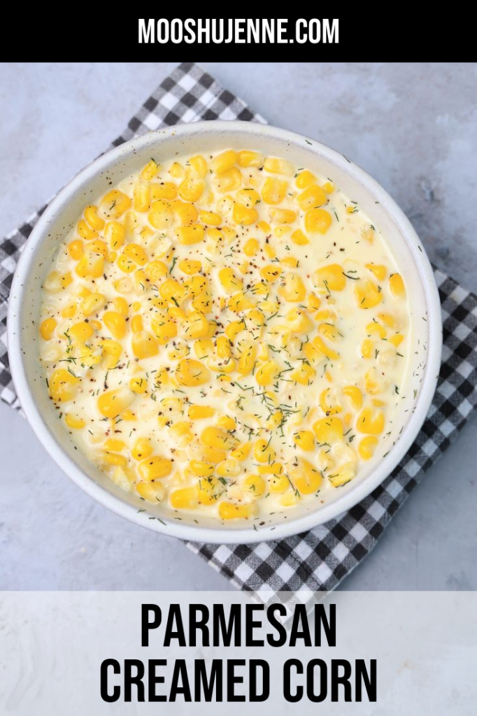 Parmesan Creamed Corn in a stone dish with a plaid napkin on a faux concrete backdrop.