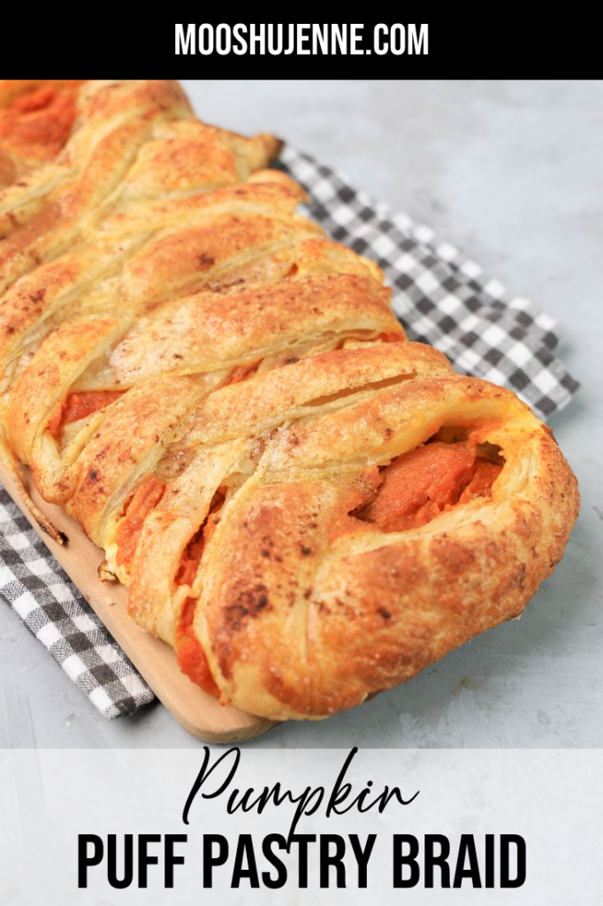 Pumpkin puff pastry braid on a plaid napkin with a faux concrete back drop.