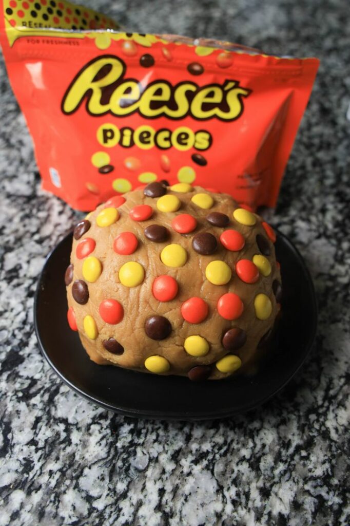 Reese's pieces on the peanut butter ball on a black plate.
