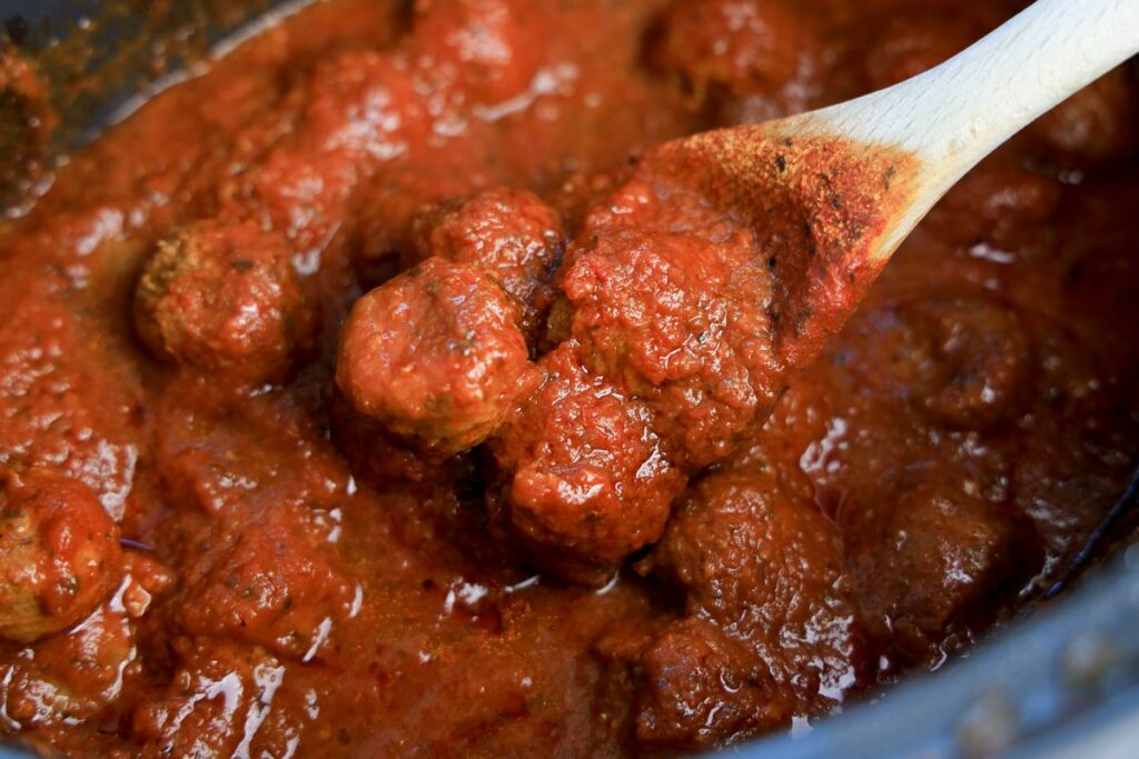 Frozen meatballs in a crockpot topped with red sauce.