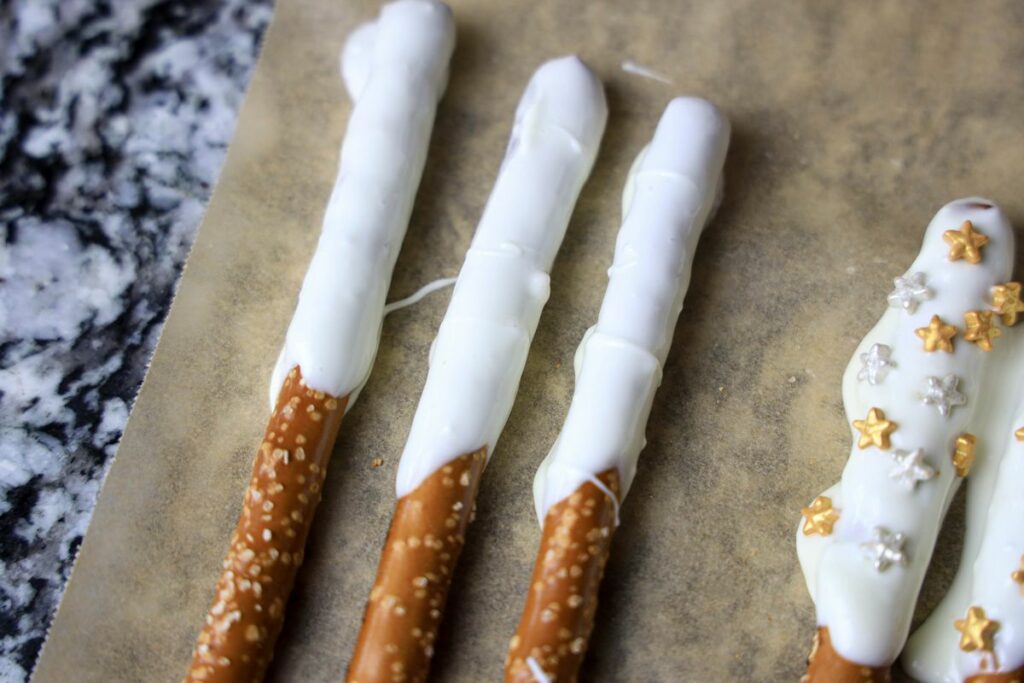 Pretzel rod with white chocolate on a piece of parchment paper.