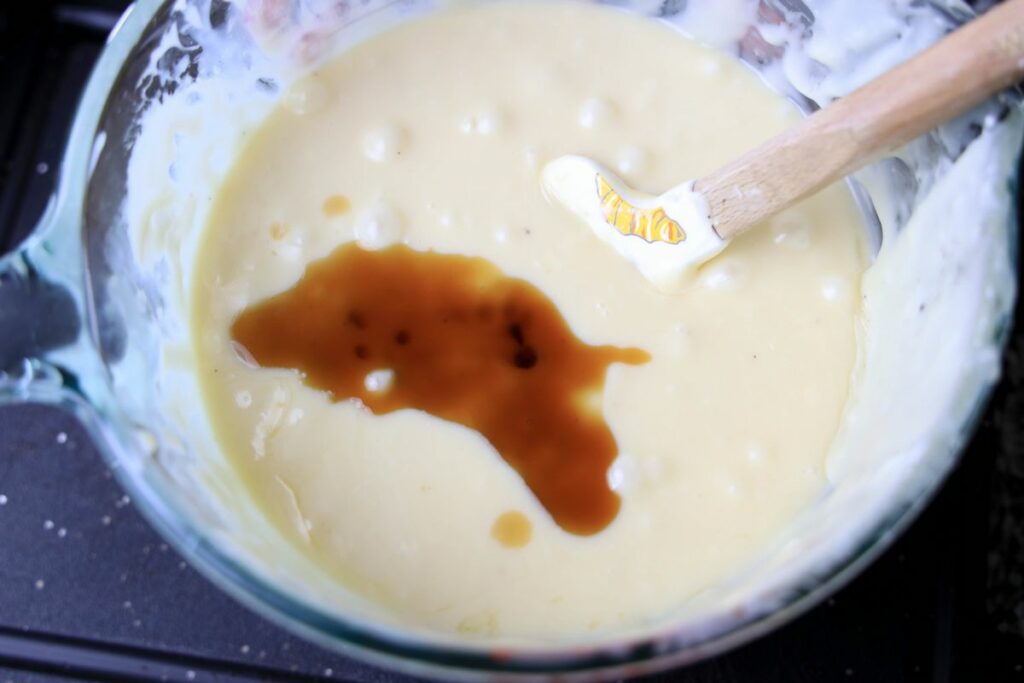 Melted white chocolate in a pyrex bowl with vanilla on top.