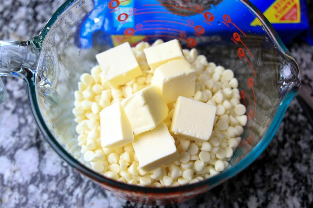 Butter on top of white chocolate chips in a pyrex bowl