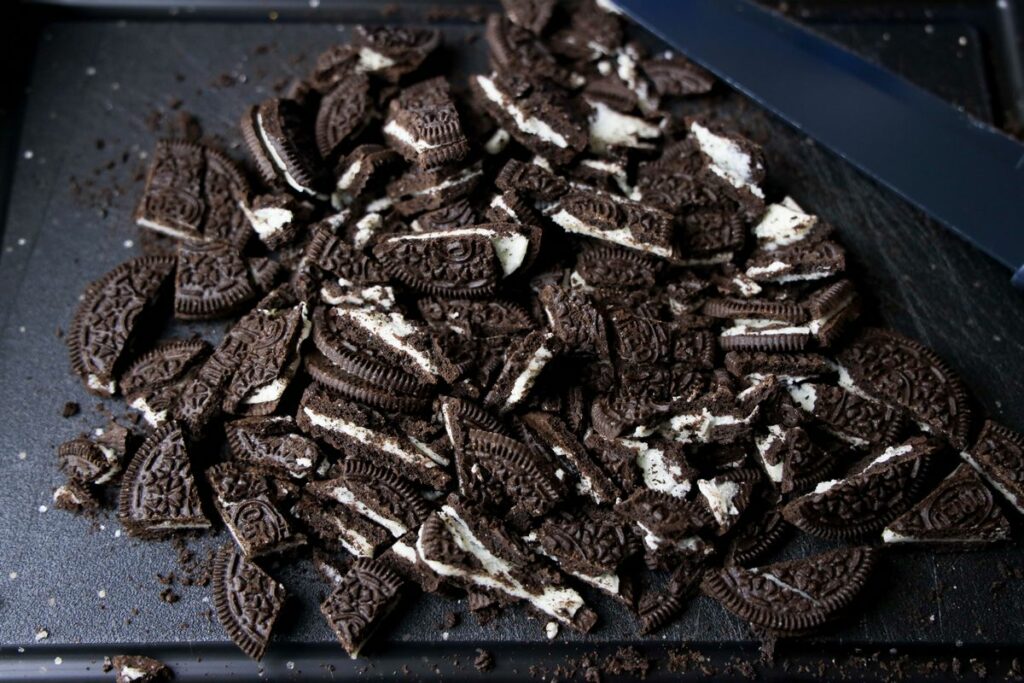 Chopped Oreo cookies on a black cutting board.