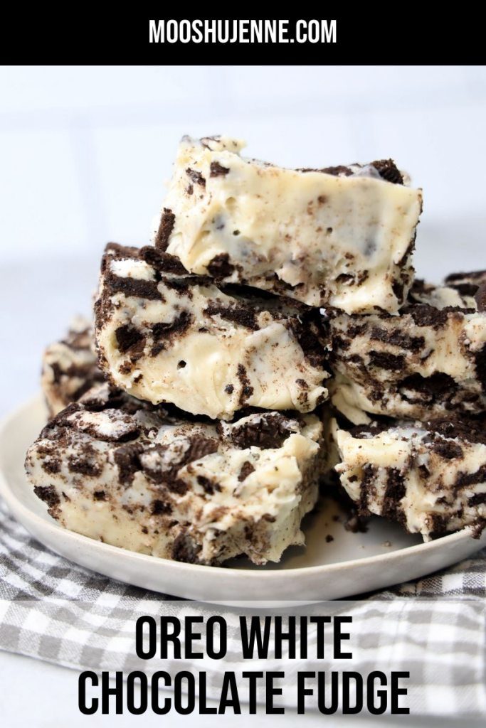 Oreo White Chocolate Fudge stacked on a white plate with gray plaid napkin on a faux concrete back drop.