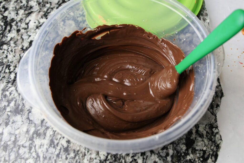 Melted Ghirardelli's chocolate wafers in a plastic bowl.