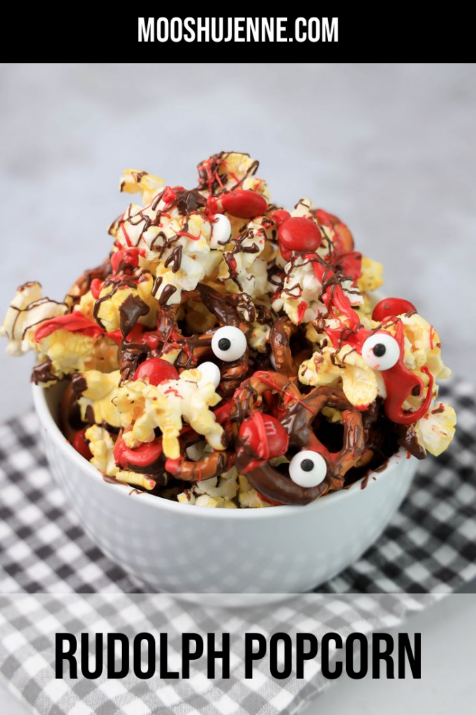Popcorn with pretzels, red M&M's, chocolate and red drizzle in a white bowl.