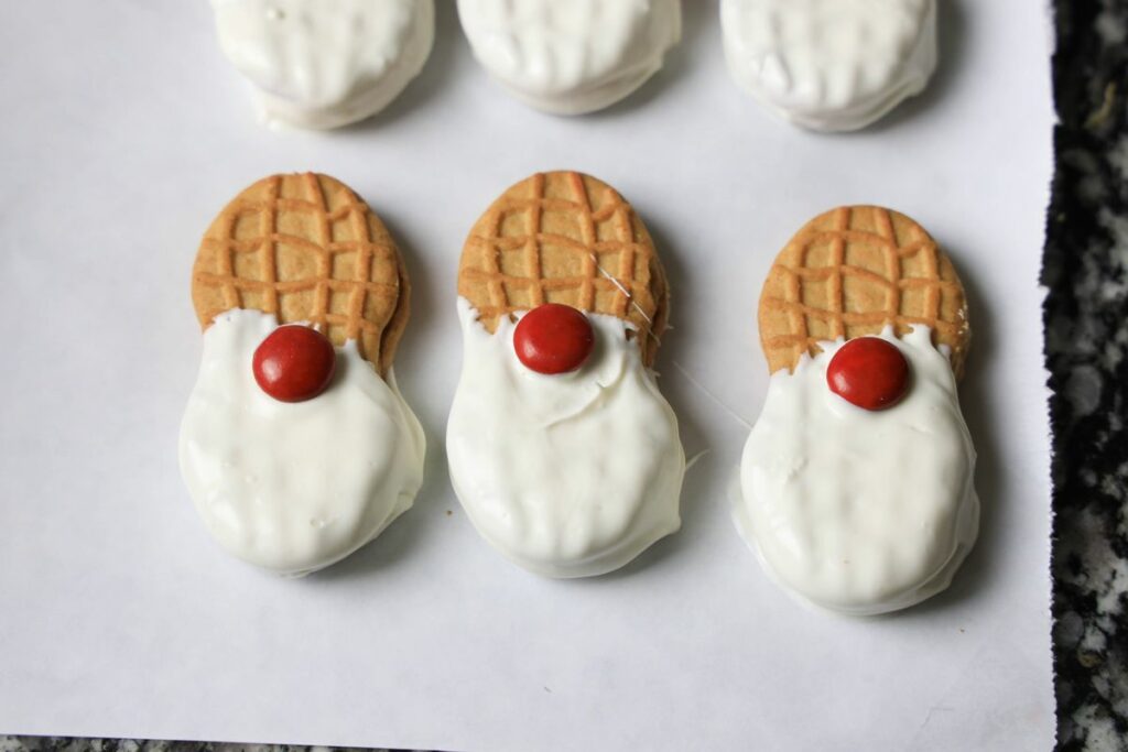 Dipped nutter butters in white chocolate with a red M&M nose.