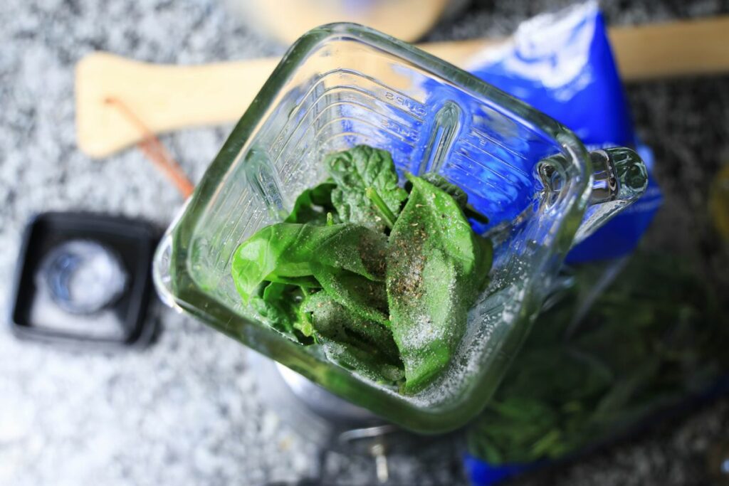 Herbs inside the blender on a counter top.