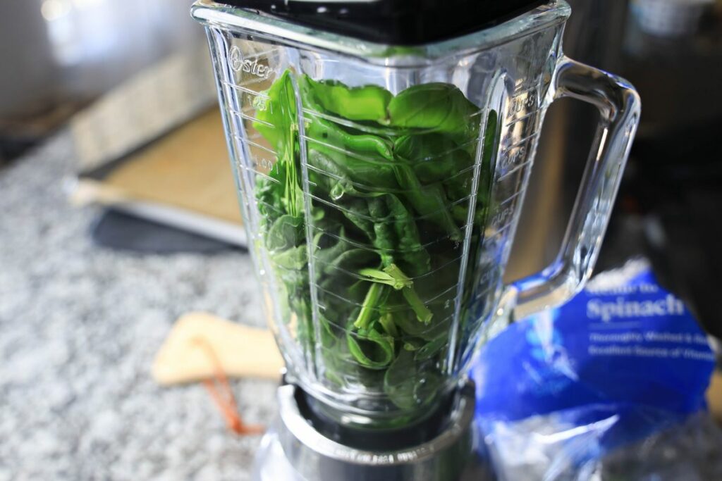 Herbs inside the blender on a counter top.