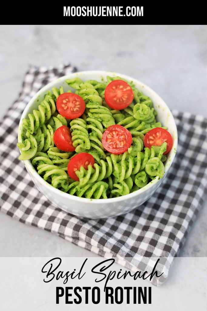 Basil Garlic Spinach Pesto Rotini topped with tomatoes in a white bowl on a gray plaid napkin.