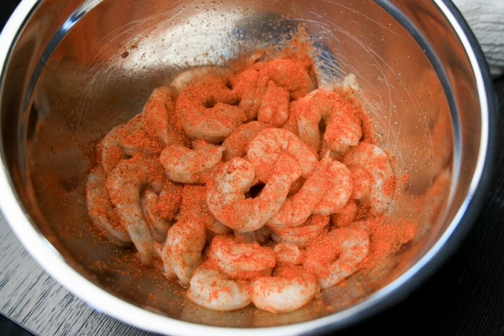 Shrimp in a bowl seasoned with blackened seasoning.