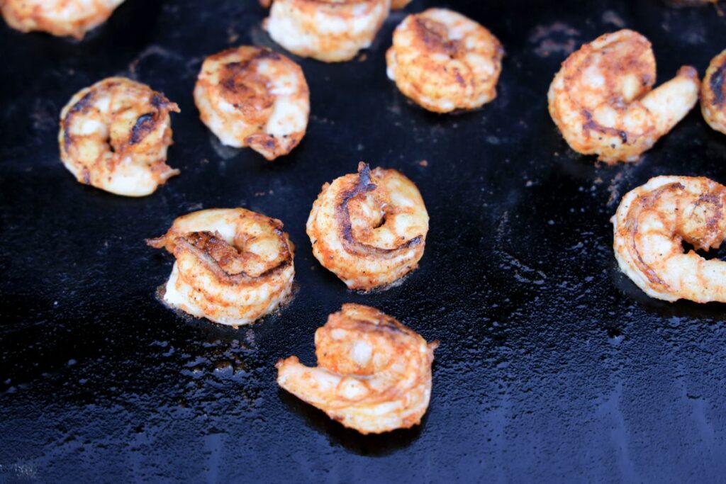 Blackened shrimp cooking on a Blackstone flat top grill.