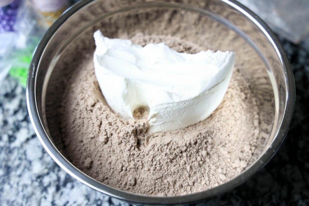 Cream cheese and brownie mix in a bowl on a counter.