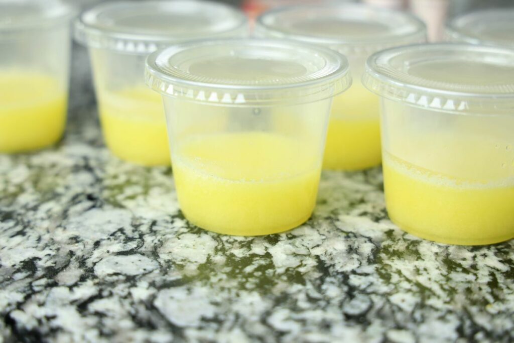 Yellow jello in a clear plastic cup.