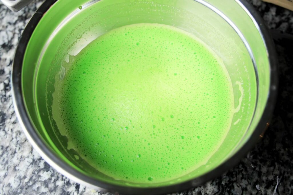 Green jello with sweetened condensed milk in a bowl.