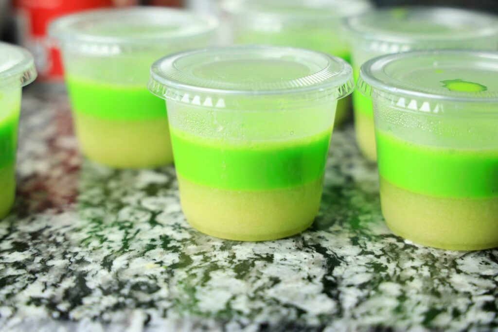 Green jello layer on top of the yellow layer in a clear cup.