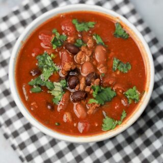 Slow Cooker Beef Chili in a stone bowl with a gray plaid napkin on a faux backdrop.