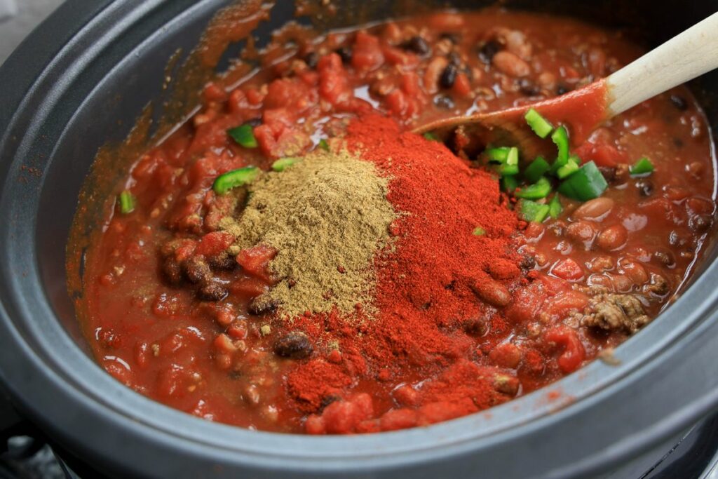 Seasonings on top of chili mixture inside the slow cooker.