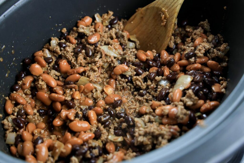 Ground beef and beans in the slow cooker stirred.