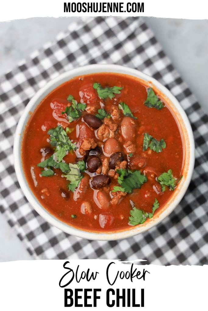 Slow Cooker Beef Chili in a stone bowl with a gray plaid napkin on a faux backdrop.