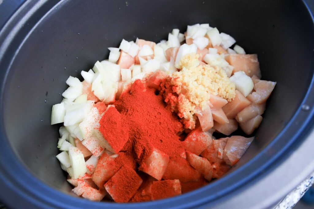 Onion, chicken, paprika, and garlic in a slow cooker.