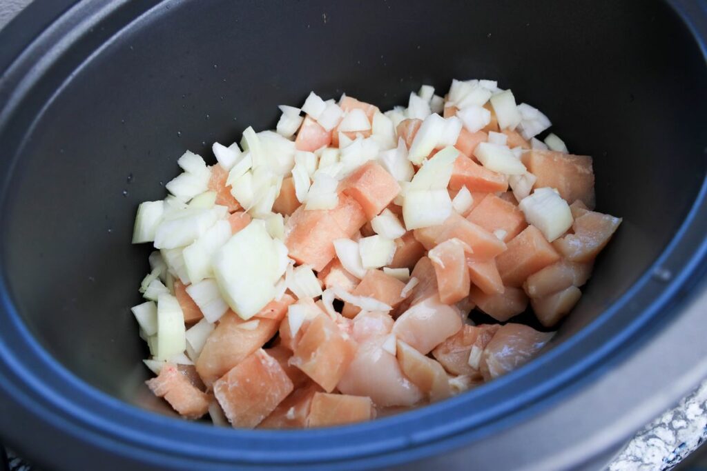 Onions and chicken in a slow cooker.