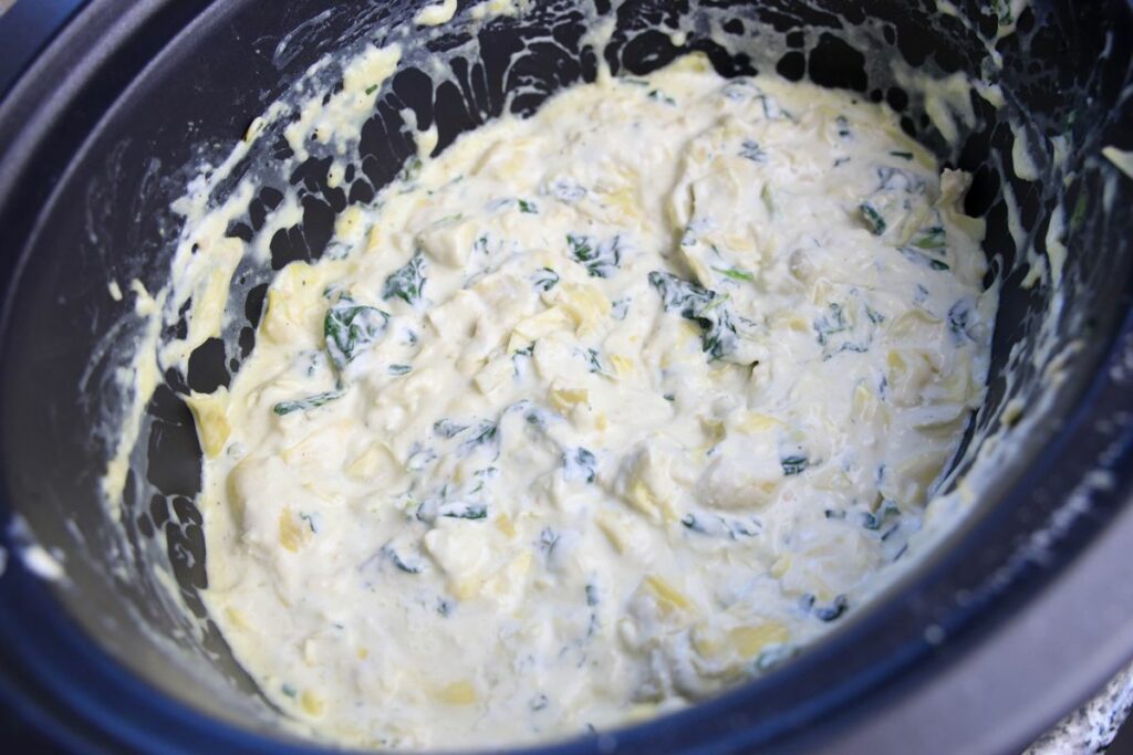 Spinach artichoke dip inside the slow cooker.