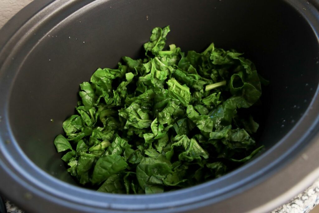 Chopped spinach inside the slow cooker.