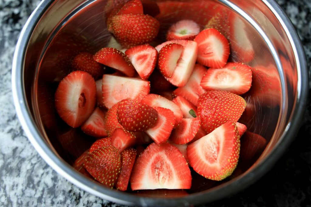 Sliced strawberries in a metal bowl.