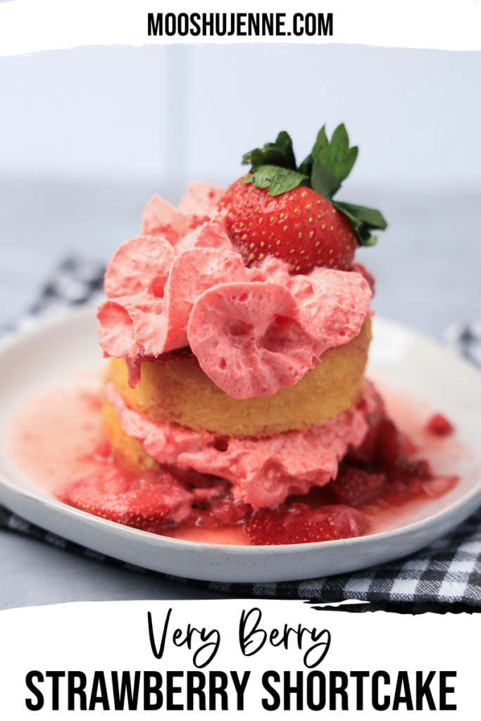 Strawberry shortcake with smashed strawberries and dessert cups with strawberry whipped topping on a white plate with gray plaid napkin.