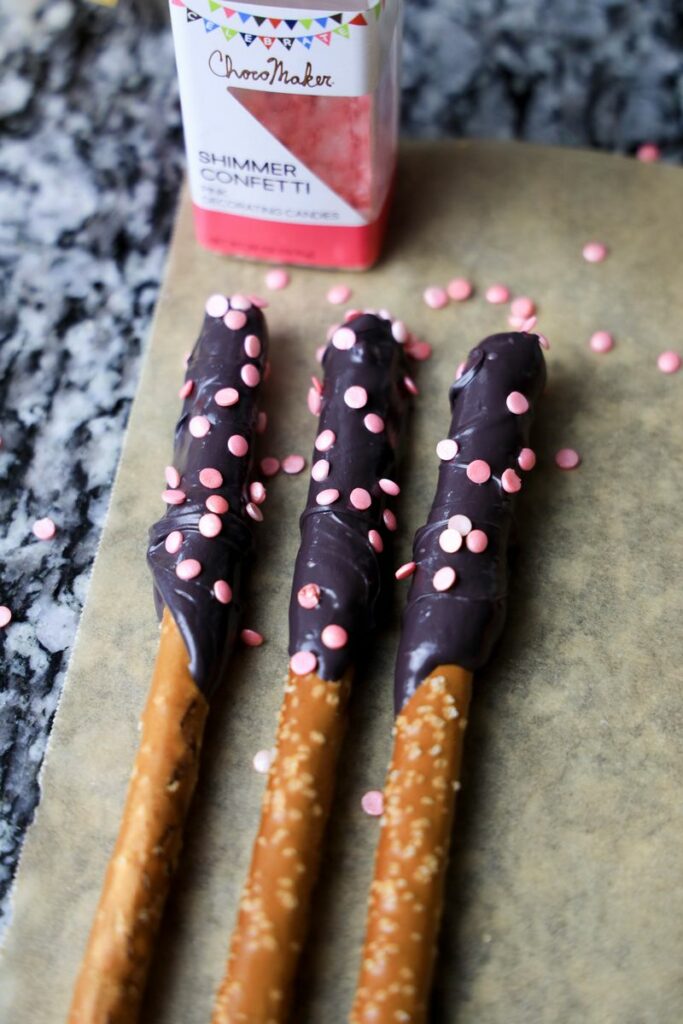 Pretzel rods coated in candy melts on a parchment paper.