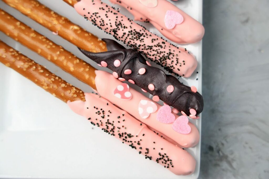 Valentine's Day Pretzel Rods on a white plate on a faux concrete backdrop.