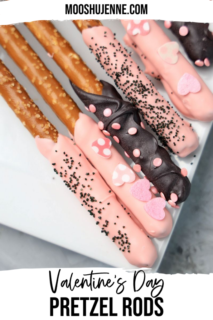 Valentine's Day Pretzel Rods on a white plate on a faux concrete backdrop.