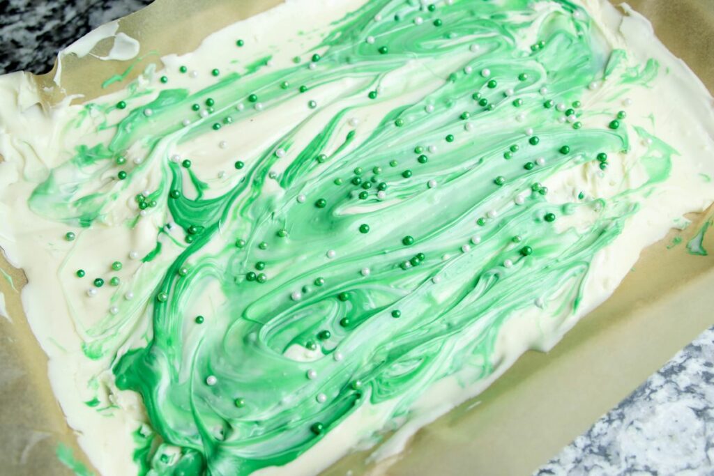 White and green candy melts swirled in on top of parchment paper. 