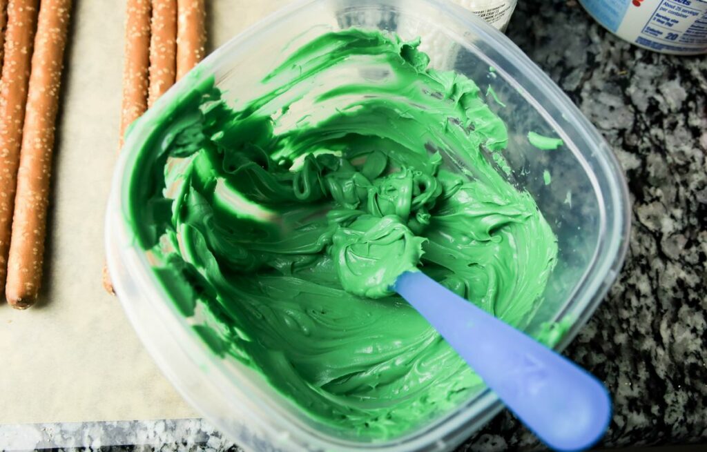 Green candy melts in a plastic bowl on the counter top.