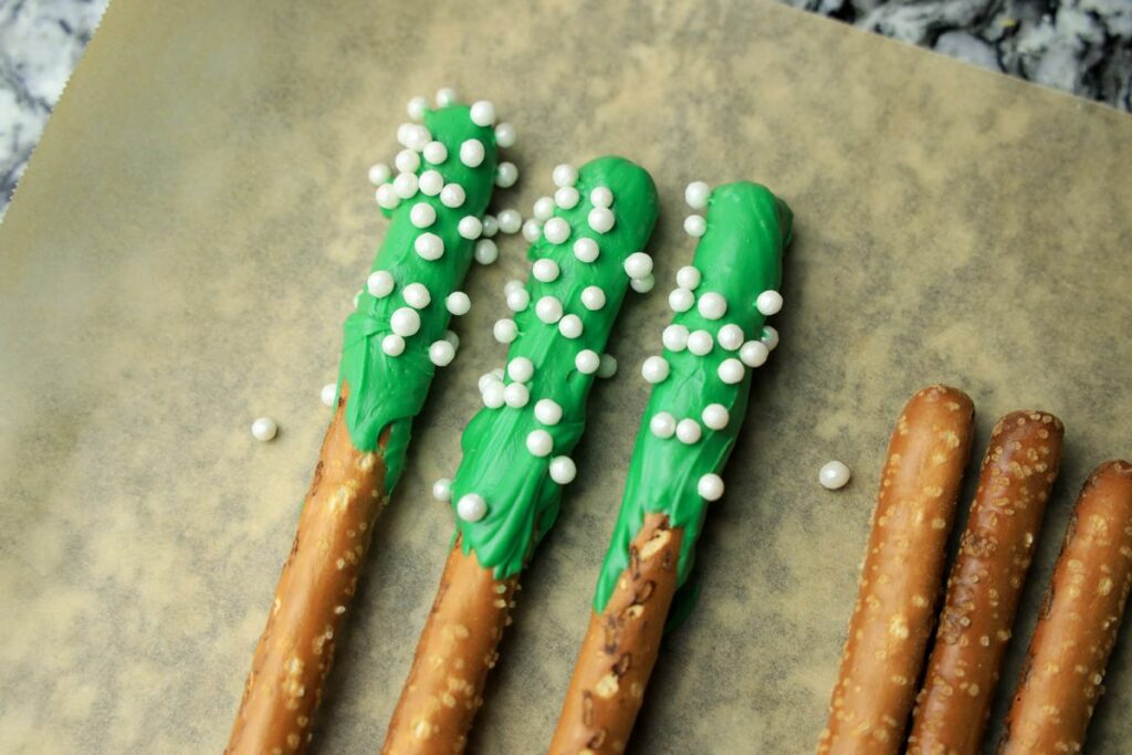 Green dipped pretzel rods on parchment paper.