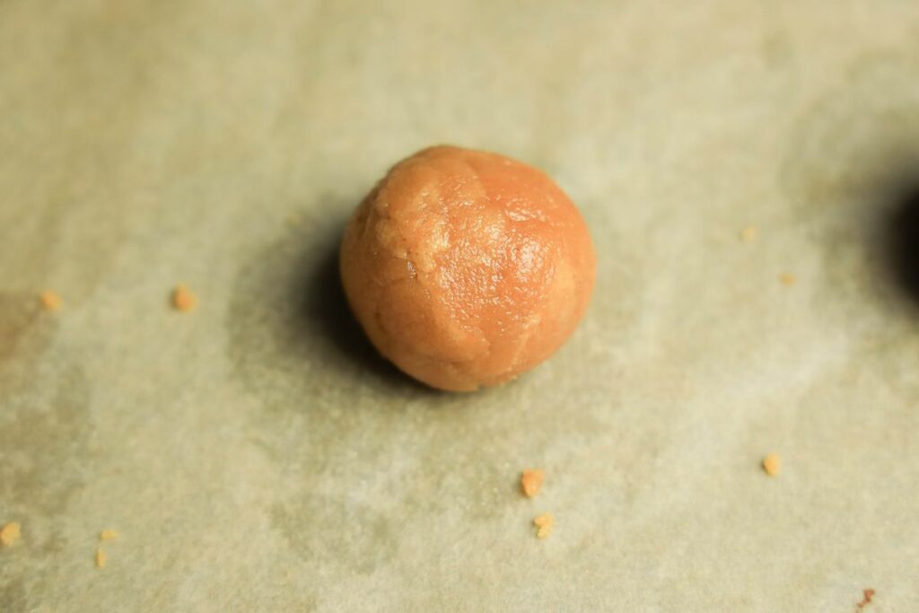 Peanut butter dough ball on a piece of parchment paper on a baking sheet.
