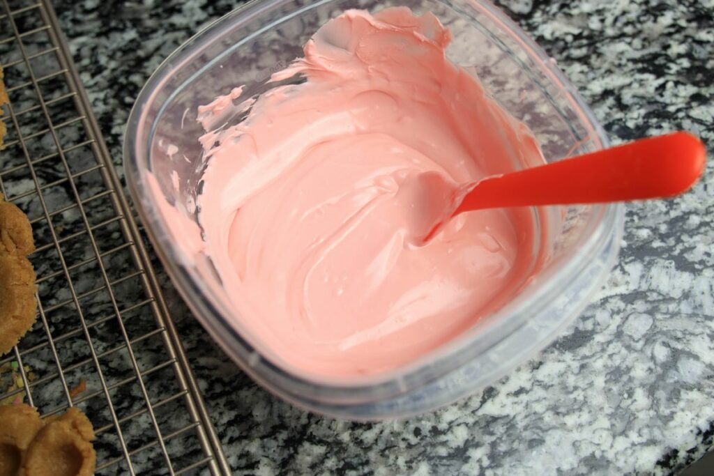 Pink candy melts melted in a plastic bowl. 