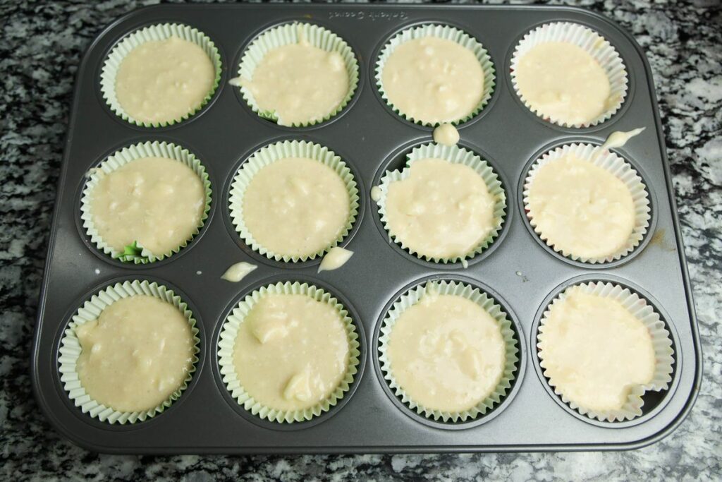 Cupcake batter in a cupcake lined baking sheet.