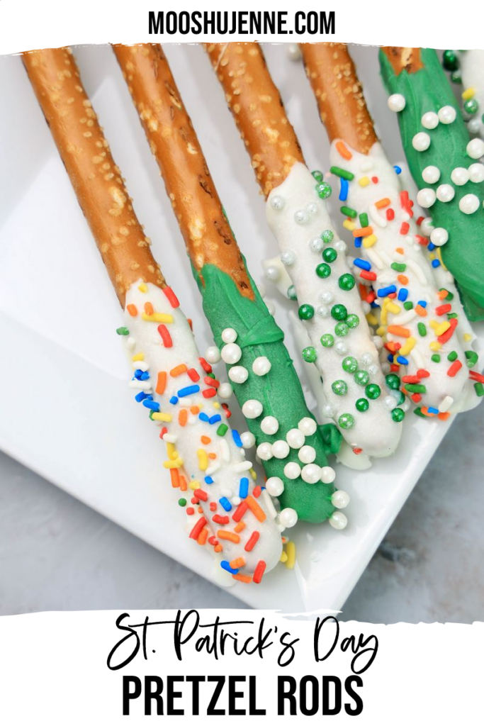 St. Patrick's Day dipped pretzel rods on a white plate on a faux concrete backdrop.