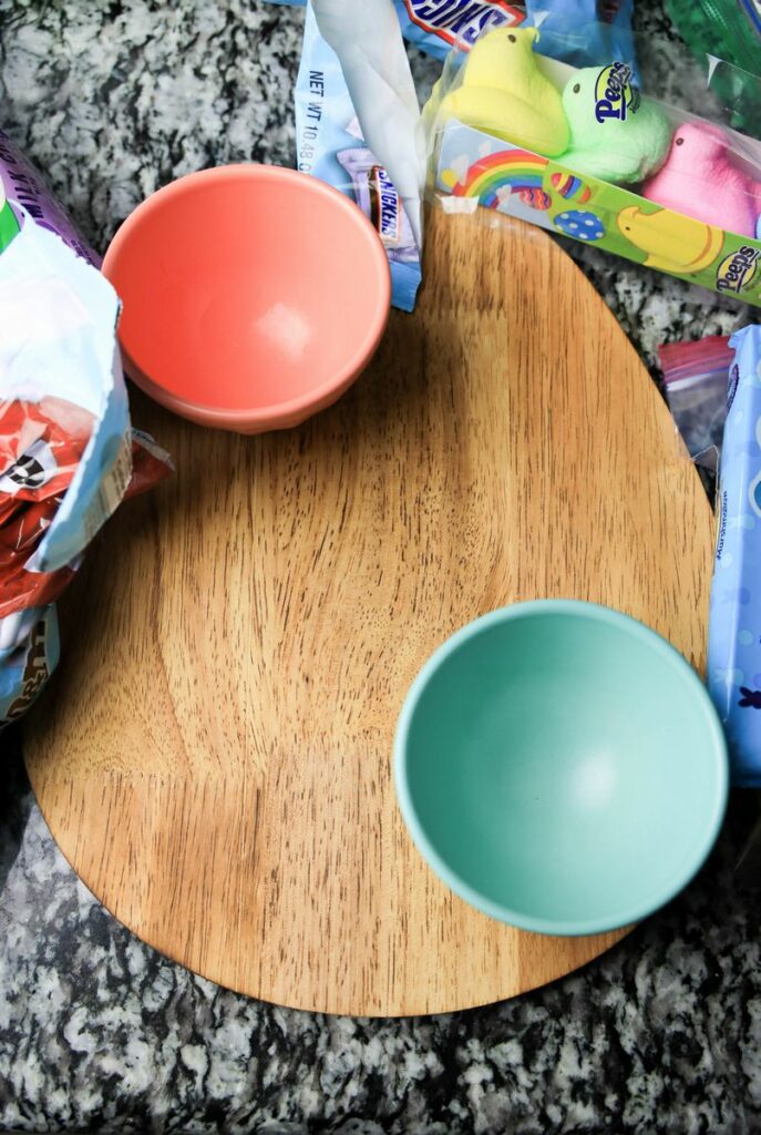 Light blue and pink bowls on a egg shaped wood board.