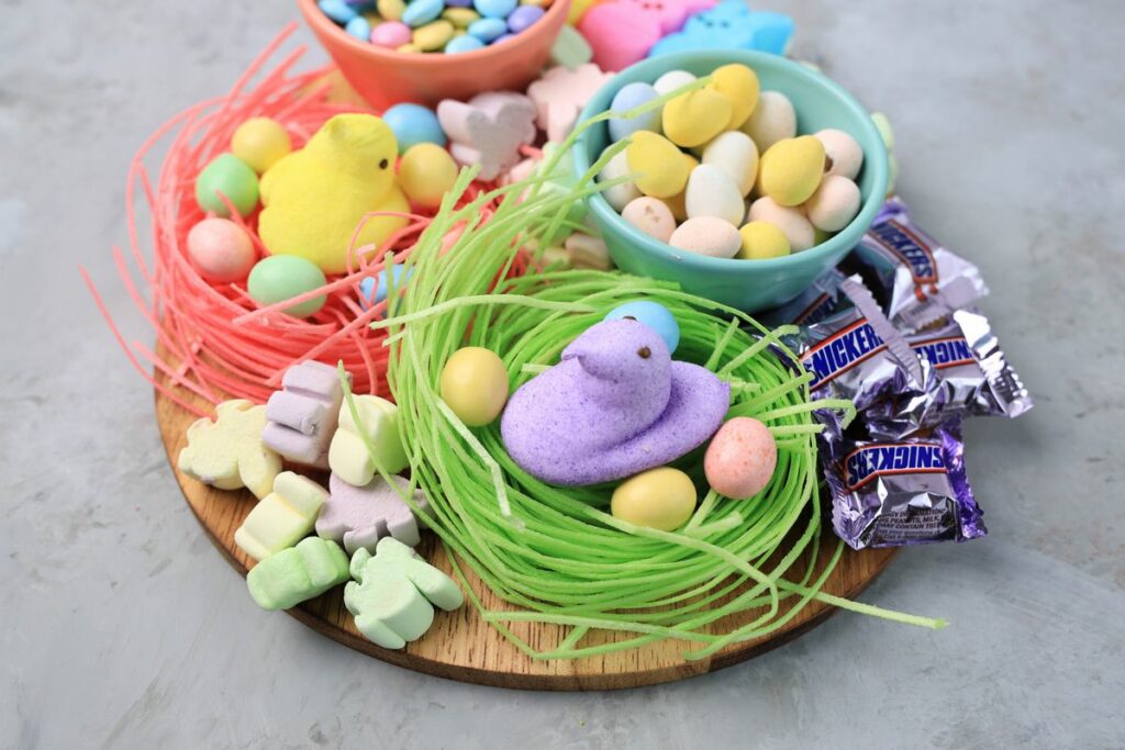 Easter Candy Charcuterie Board with peeps candy, cadbury eggs, and m&m's on an egg shaped board.