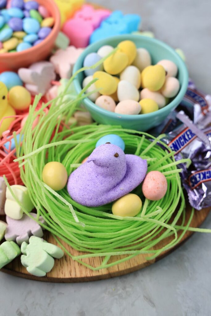 Easter Candy Charcuterie Board with peeps candy, cadbury eggs, and m&m's on an egg shaped board.