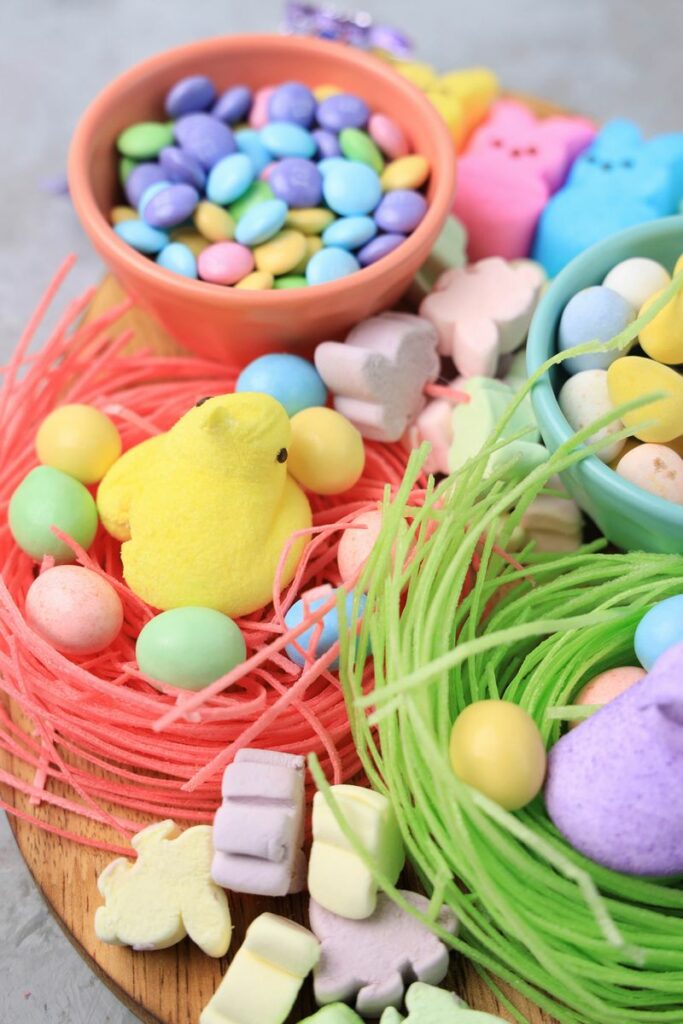 Easter Candy Charcuterie Board with peeps candy, cadbury eggs, and m&m's on an egg shaped board.