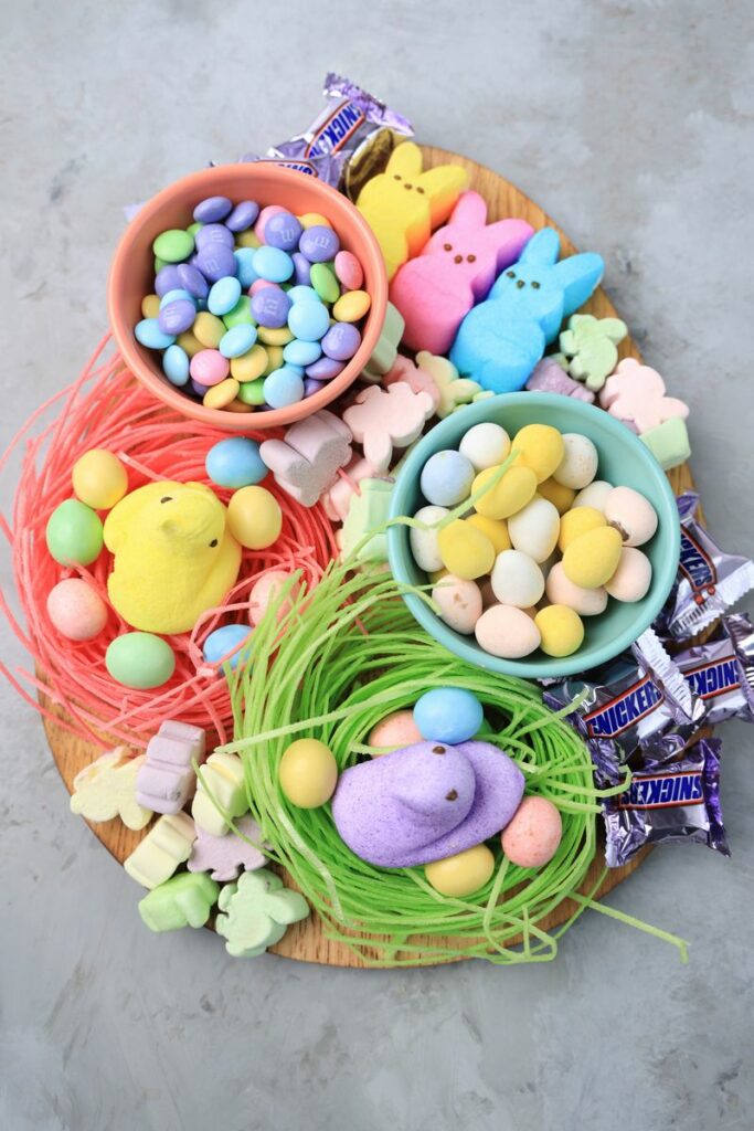 Easter Candy Charcuterie Board with peeps candy, cadbury eggs, and m&m's on an egg shaped board.
