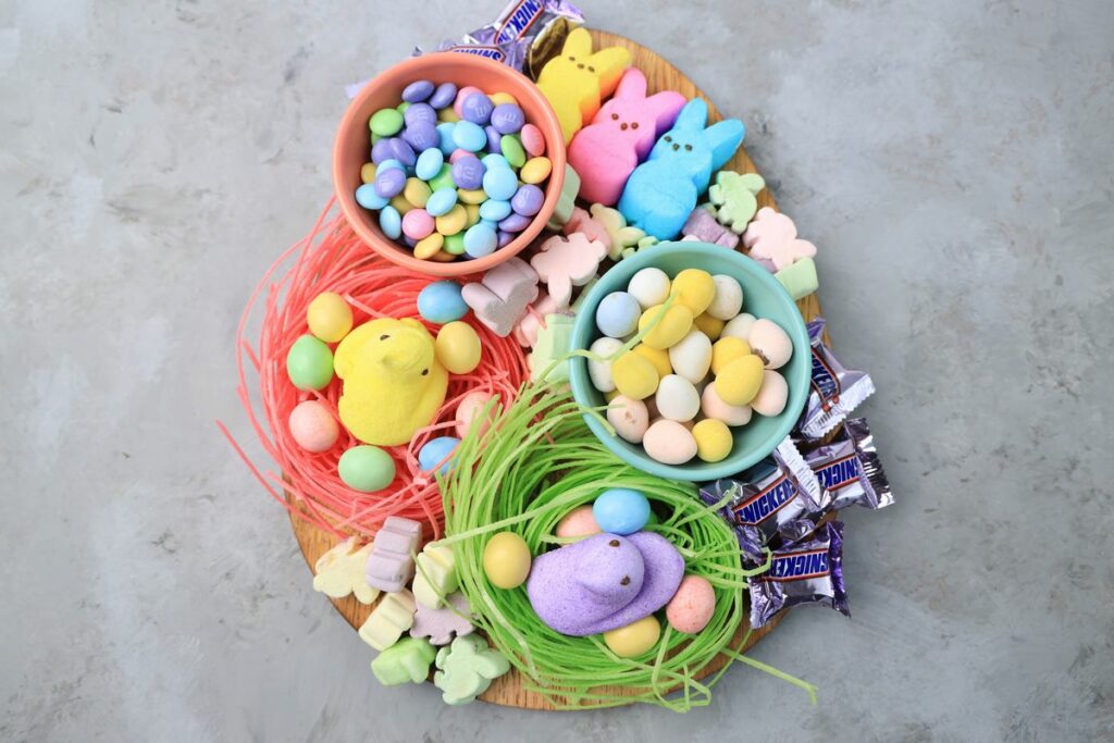 Easter Candy Charcuterie Board with peeps candy, cadbury eggs, and m&m's on an egg shaped board.